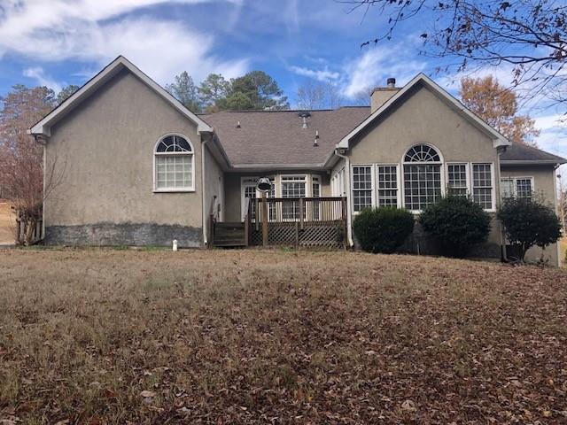 rear view of house featuring a lawn and a deck