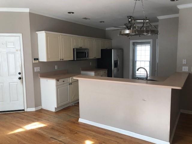 kitchen with sink, kitchen peninsula, light hardwood / wood-style floors, appliances with stainless steel finishes, and ornamental molding