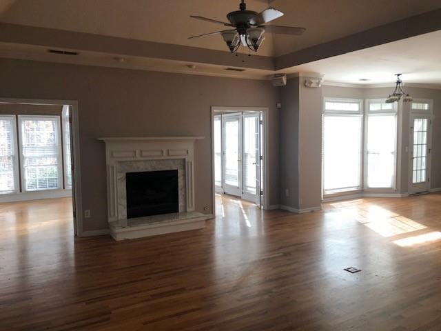 unfurnished living room with ceiling fan with notable chandelier, wood-type flooring, and a high end fireplace