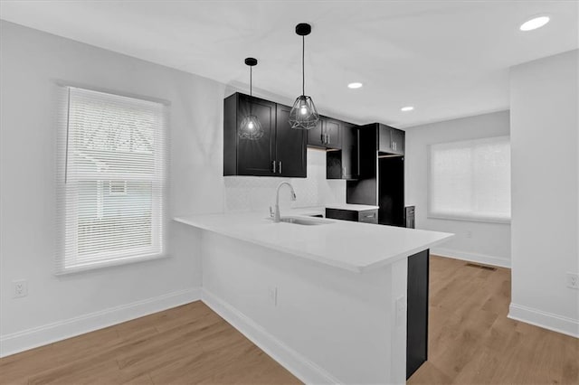 1222 E Forrest Ave, Atlanta, GA 30344 - kitchen with a sink, decorative backsplash, baseboards, dark cabinets, and light wood-style floors