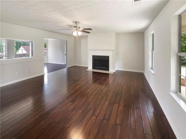 727 Overlook Crst, Monroe, GA 30655 - unfurnished living room with plenty of natural light, dark wood-style floors, a fireplace with flush hearth, ceiling fan, and a textured ceiling