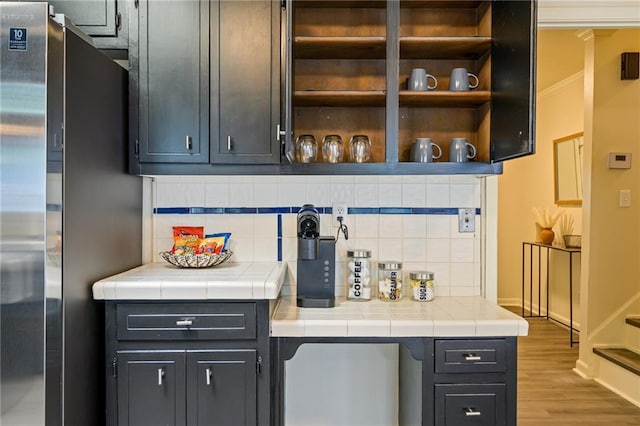 bar featuring decorative backsplash, wood finished floors, baseboards, and freestanding refrigerator