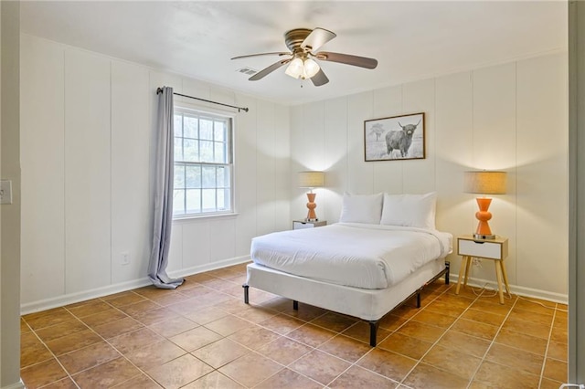 bedroom with tile patterned flooring, a decorative wall, baseboards, and ceiling fan