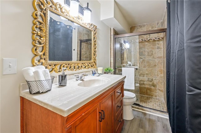 bathroom featuring a stall shower, toilet, vanity, and wood finished floors