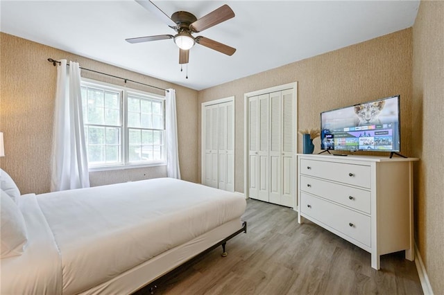 bedroom featuring ceiling fan, two closets, and wood finished floors