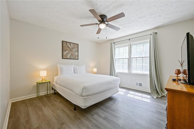 bedroom with wood finished floors, visible vents, and a textured ceiling