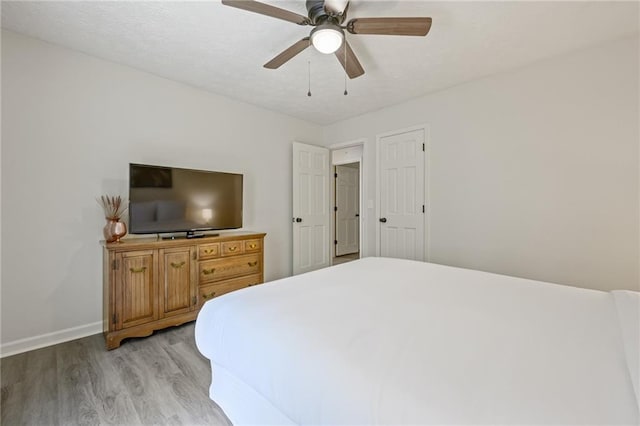 bedroom with light wood-style flooring, a ceiling fan, and baseboards