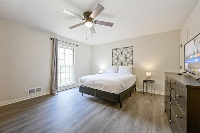 bedroom featuring visible vents, a ceiling fan, baseboards, and wood finished floors