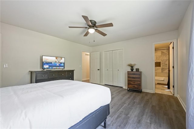 bedroom with wood finished floors, baseboards, ceiling fan, a closet, and connected bathroom