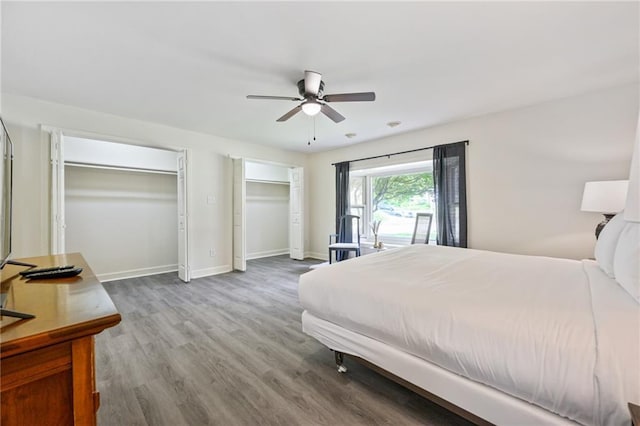 bedroom featuring ceiling fan, baseboards, two closets, and wood finished floors