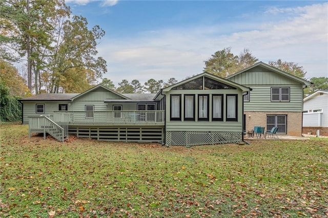 back of property featuring a yard, brick siding, and a deck