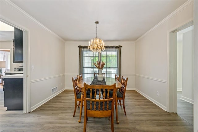 dining area featuring crown molding, a notable chandelier, wood finished floors, and visible vents