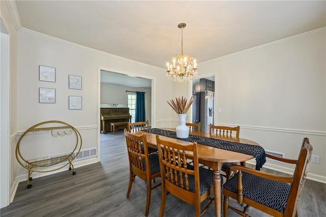 dining room featuring ornamental molding, baseboards, an inviting chandelier, and wood finished floors