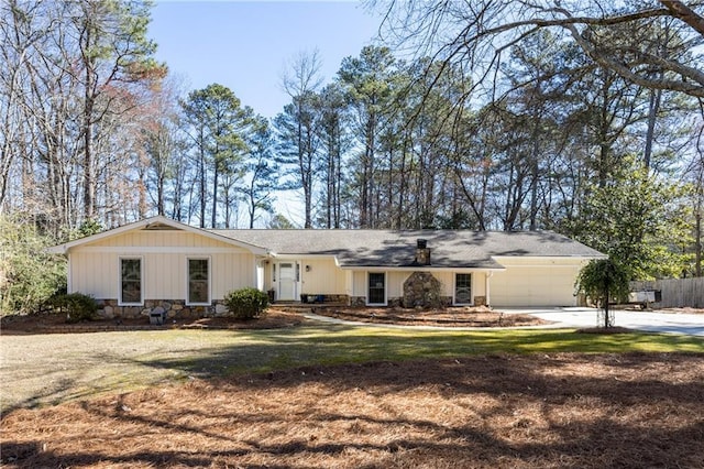 ranch-style house featuring concrete driveway, an attached garage, a front yard, fence, and stone siding