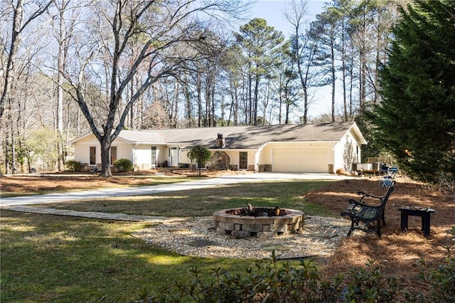 ranch-style home featuring a garage, driveway, and a fire pit