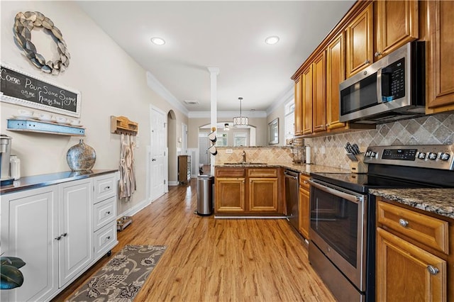 240 Daisy Cir, Mcdonough, GA 30252 - kitchen featuring appliances with stainless steel finishes, brown cabinetry, a peninsula, decorative backsplash, and crown molding