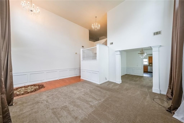 5280 Lakerock Way S, Fulton, GA 30331 - carpeted empty room featuring a chandelier, a towering ceiling, a decorative wall, and a wainscoted wall