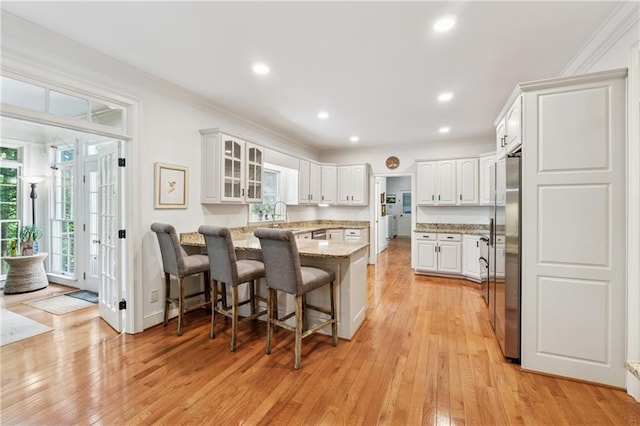 34 Johnston Row NW, Cartersville, GA 30121 - kitchen with a peninsula, ornamental molding, a kitchen bar, light wood finished floors, and light stone countertops