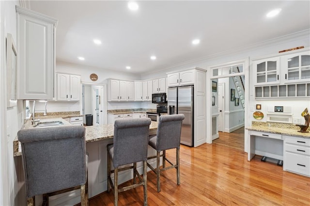 34 Johnston Row NW, Cartersville, GA 30121 - kitchen featuring appliances with stainless steel finishes, a peninsula, a breakfast bar, crown molding, and white cabinets
