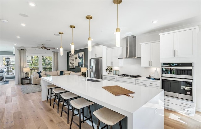 1105 Rivard Cir NW, Atlanta, GA 30318 - kitchen with wall chimney range hood, stainless steel appliances, a spacious island, recessed lighting, and white cabinetry
