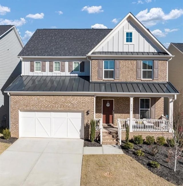 view of front facade with concrete driveway, a porch, a standing seam roof, and brick siding