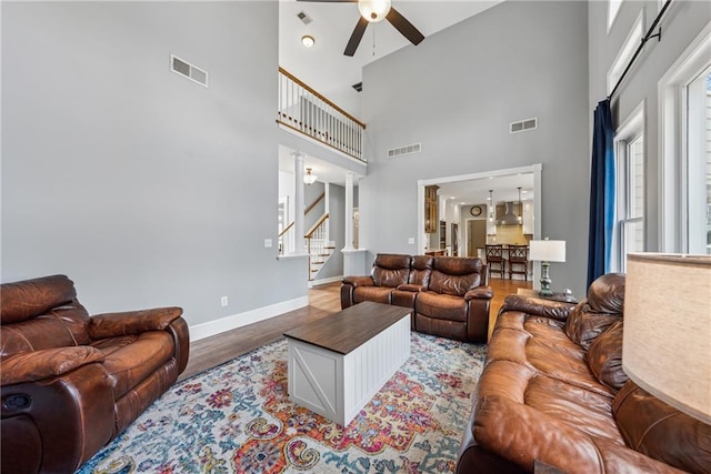 living area with stairs, ceiling fan, wood finished floors, and visible vents