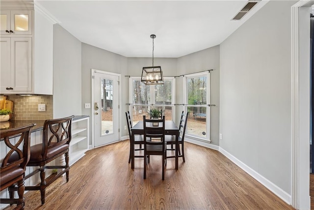 dining area featuring a chandelier, wood finished floors, visible vents, and baseboards