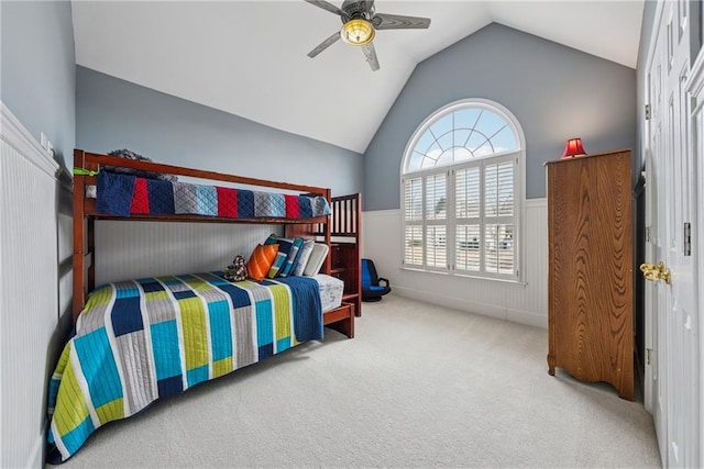 bedroom featuring a ceiling fan, lofted ceiling, a wainscoted wall, and carpet flooring