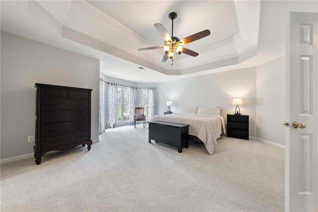 bedroom with a tray ceiling, carpet flooring, a ceiling fan, and baseboards