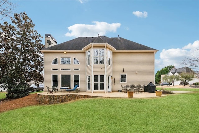 back of house with a chimney, a lawn, and a patio