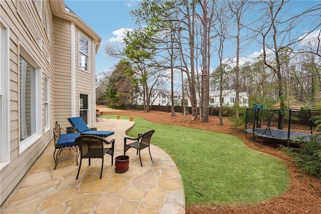 view of yard with a trampoline, a patio area, and fence