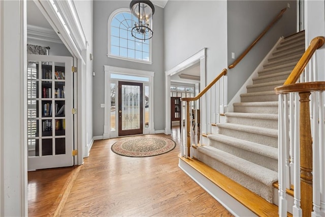 entryway with a notable chandelier, a high ceiling, wood finished floors, baseboards, and stairs