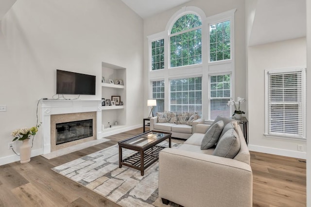 1547 Trilogy Park, Hoschton, GA 30548 - living area featuring a towering ceiling, built in features, baseboards, a fireplace, and wood finished floors