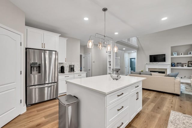 1547 Trilogy Park, Hoschton, GA 30548 - kitchen featuring stainless steel fridge, light wood finished floors, a kitchen island, white cabinetry, and a fireplace