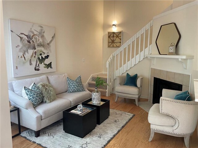 living area featuring stairway, baseboards, wood finished floors, and a tile fireplace