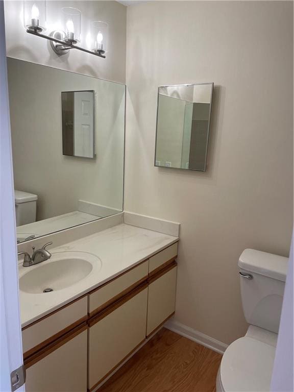 bathroom with baseboards, vanity, toilet, and wood finished floors