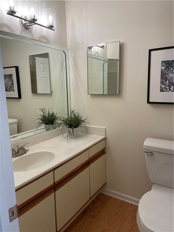 bathroom with vanity, baseboards, wood finished floors, and toilet