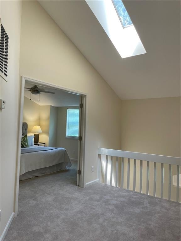 carpeted bedroom with baseboards and vaulted ceiling with skylight