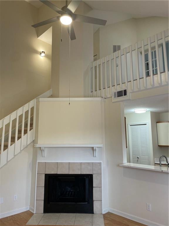 unfurnished living room featuring high vaulted ceiling, a fireplace, a ceiling fan, visible vents, and baseboards