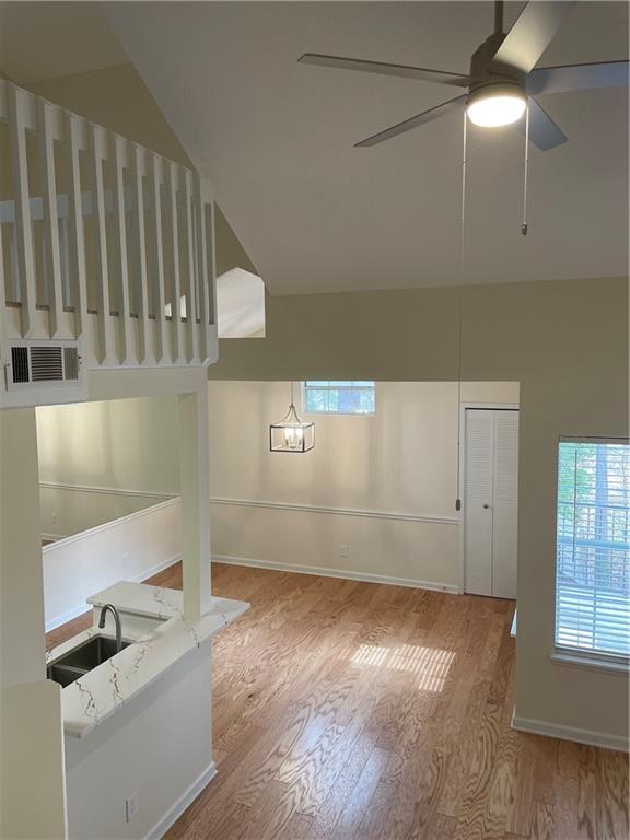 interior space featuring visible vents, a ceiling fan, vaulted ceiling, wood finished floors, and baseboards