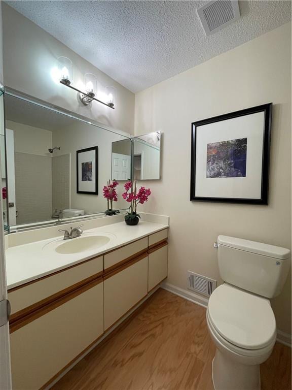 bathroom featuring baseboards, toilet, a textured ceiling, and visible vents