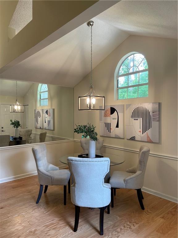 dining area featuring vaulted ceiling, an inviting chandelier, and wood finished floors
