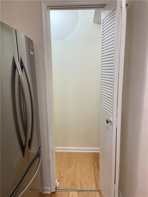 interior space featuring wood finished floors, freestanding refrigerator, and baseboards