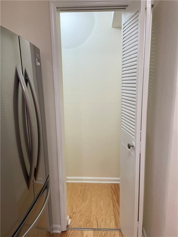 interior space with freestanding refrigerator, baseboards, and light wood-style flooring