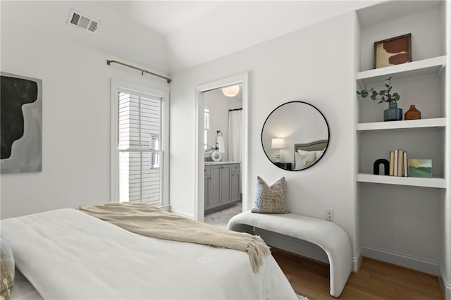 bedroom with ensuite bathroom, lofted ceiling, and light hardwood / wood-style flooring