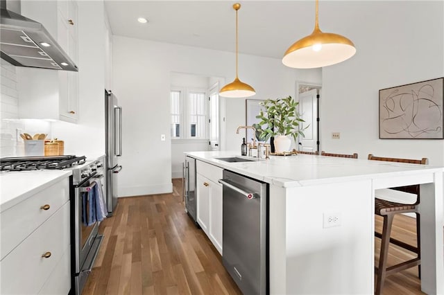 kitchen featuring pendant lighting, wall chimney exhaust hood, sink, and stainless steel appliances