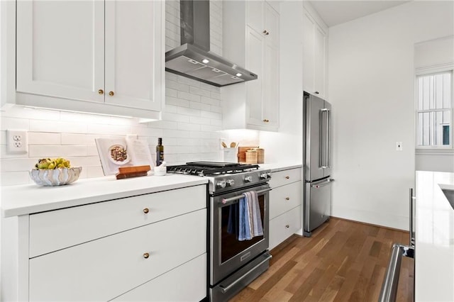 kitchen featuring white cabinets, wall chimney exhaust hood, appliances with stainless steel finishes, and tasteful backsplash