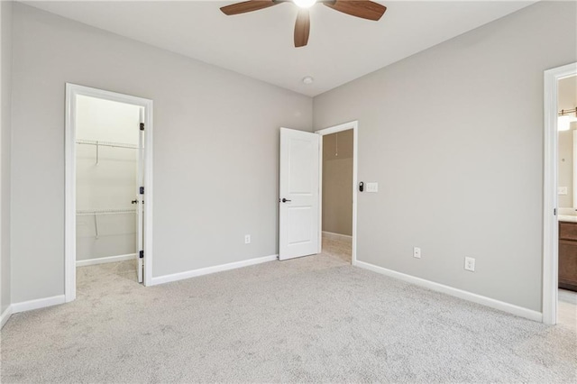 unfurnished bedroom with carpet floors, baseboards, a walk in closet, and connected bathroom