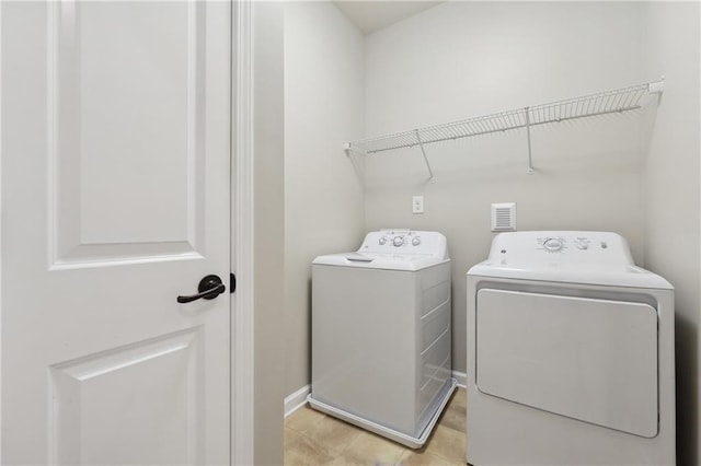 clothes washing area with laundry area, washing machine and dryer, and baseboards