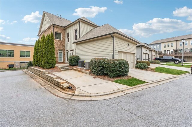 view of front facade with a residential view, concrete driveway, brick siding, and an attached garage